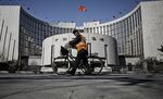 A man pushes a bicycle past the People's Bank of China (PBOC) headquarters in Beijing.
