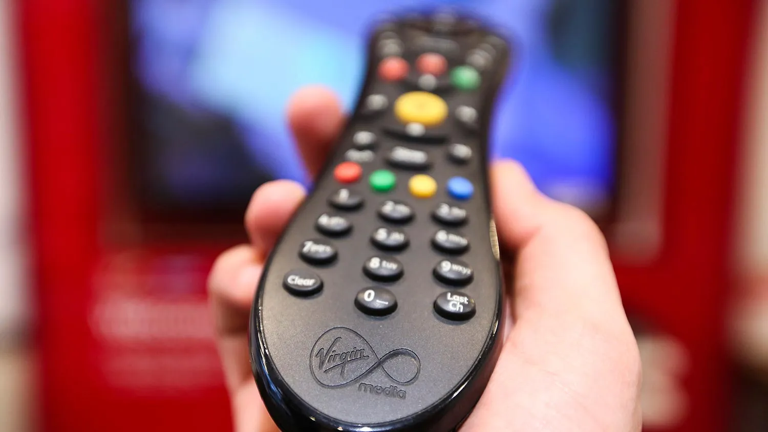 A man holds a television remote control unit for a Virgin Media set top box in this arranged photograph at the company's store on Oxford Street in London, U.K., on Wednesday, Feb. 6, 2013. Billionaire John Malone's Liberty Global Inc. agreed to acquire Virgin Media, Britain's second-largest pay-TV provider, in a $16 billion cash-and-stock transaction announced in the U.S. yesterday.
