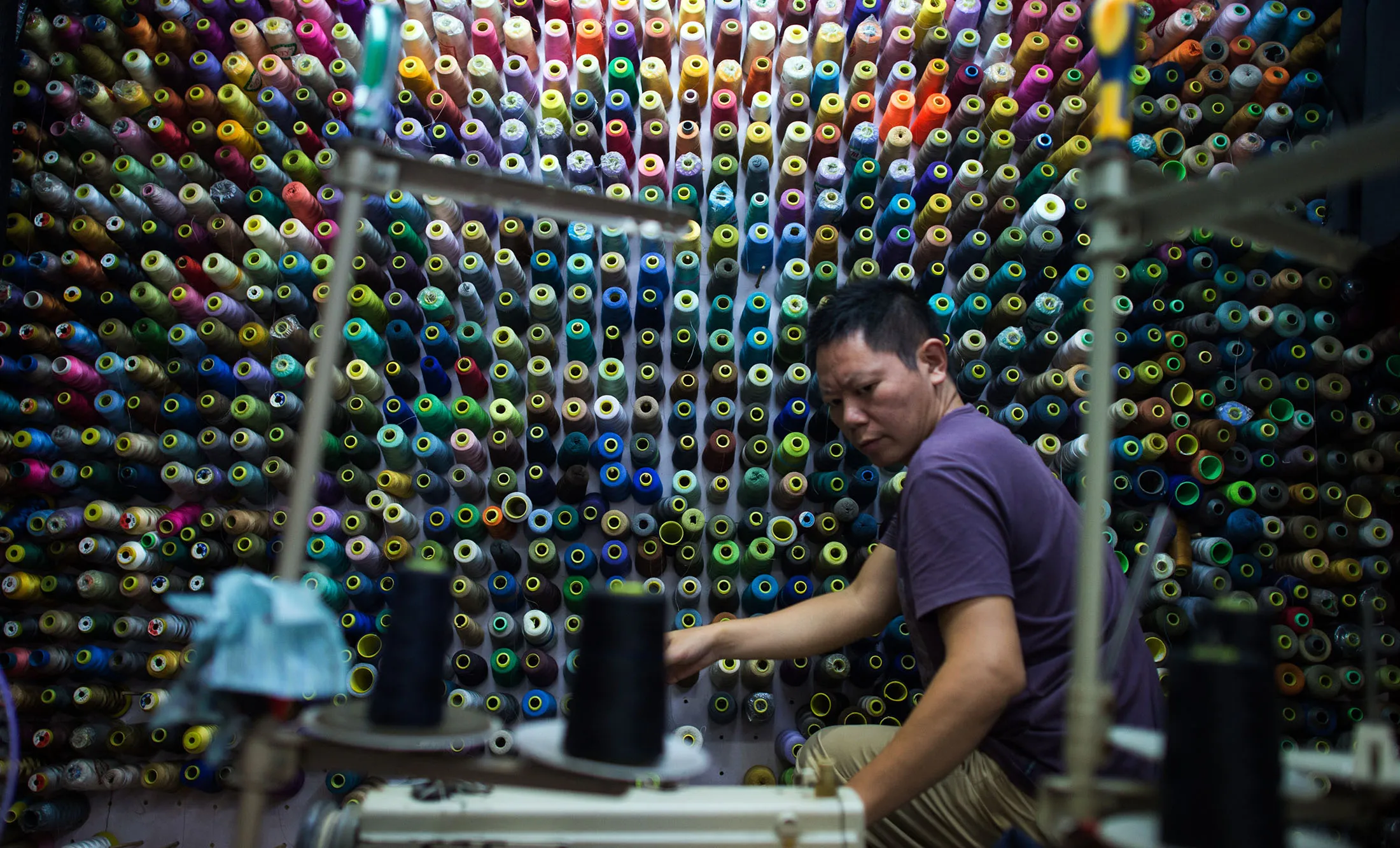 A tailor uses a sewing machine in his shop in Shanghai. A private survey says that China’s economy isn’t as weak as it may look.

