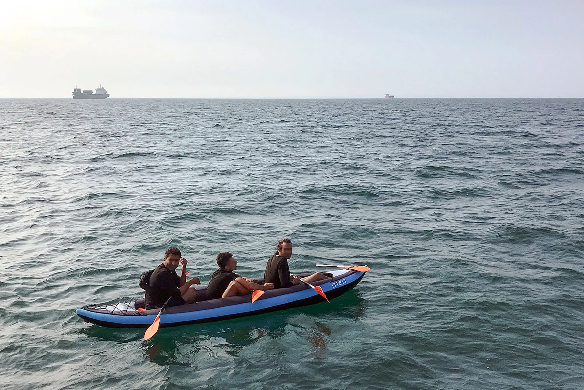 Three migrants drift in an inflatable canoe off the French coast at Calais on August 4.