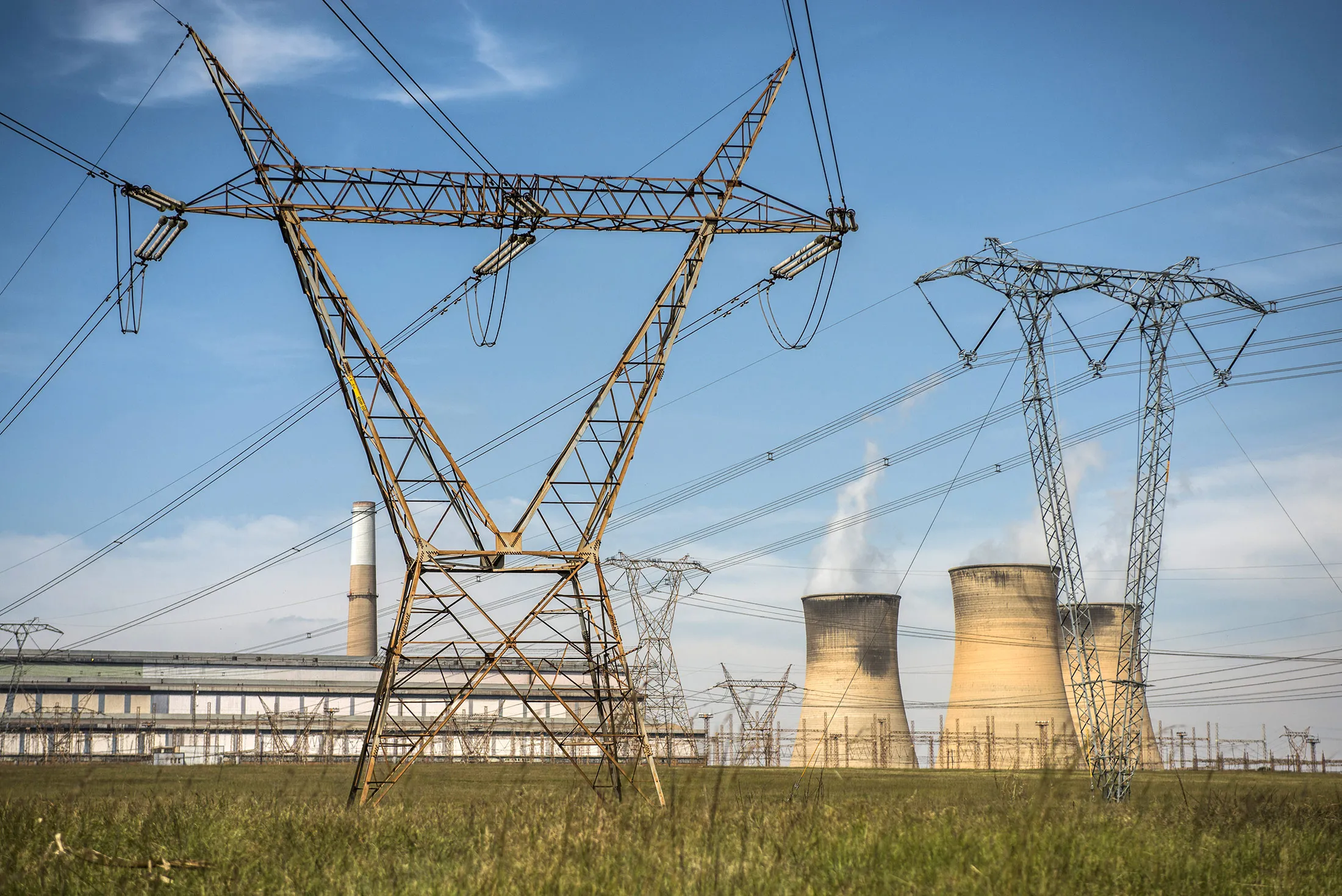 Electricity pylons carry high voltage power lines from the Hendrina power station, operated by Eskom Holdings SOC Ltd., in Middelburg, South Africa, on Wednesday, April 13, 2016. Creditors of Glencore's Optimum Coal mine approved a plan to sell it to a company controlled by South African President Jacob Zuma's son and the Gupta family on Friday, according to an administrator of the business-rescue team.
