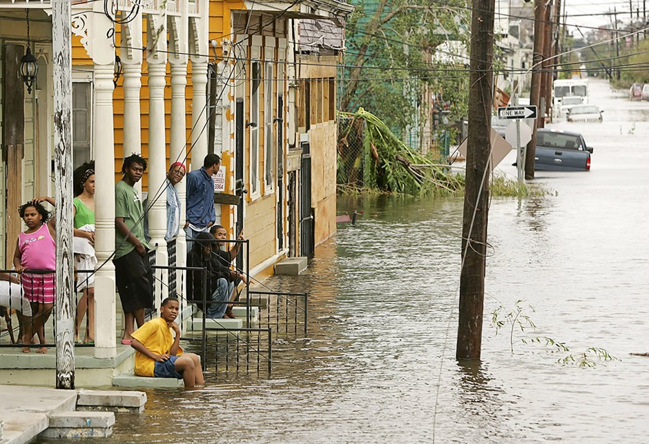 A family sits on their porch in the Treme area of New Orleans, which lies under several feet of water after Hurricane Katrina hit August 29, 2005.
