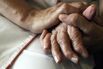 A nurse holds the hands of a person suff
