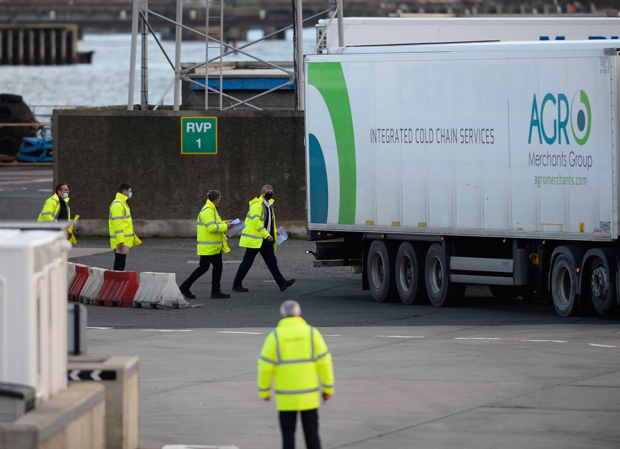Employees walk near trucks at the Port of Larne in Larne, U.K.
