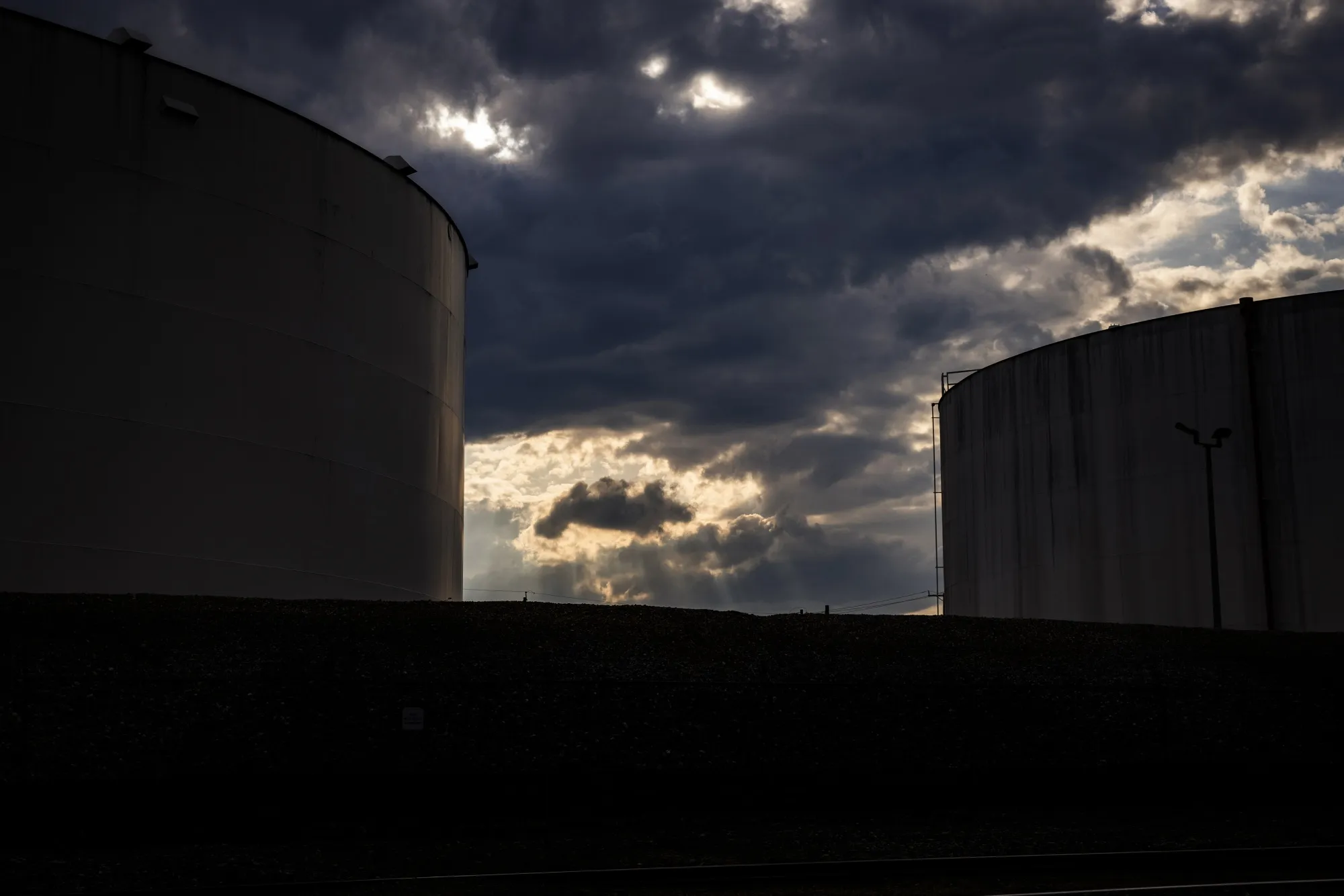Fuel storage tanks beneath a dramatic sky.