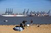 A family play a game of football beyond container ships on the dockside at the Port of Felixstowe in Harwich, U.K.