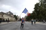 A protester waves a French flag featuring the Presidency of the Republic coat of arms, near Place Joffre during a demonstration against France's Covid-19 health pass in Paris, France, on Saturday, Aug. 7, 2021.