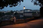 Sightseers stand on the city's old fortifications at dusk in Luxembourg.