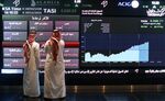 Visitors stand and watch stock movements displayed on large video screens inside the Saudi Stock Exchange, also known as the Tadawul All Share Index in Riyadh, Saudi Arabia.