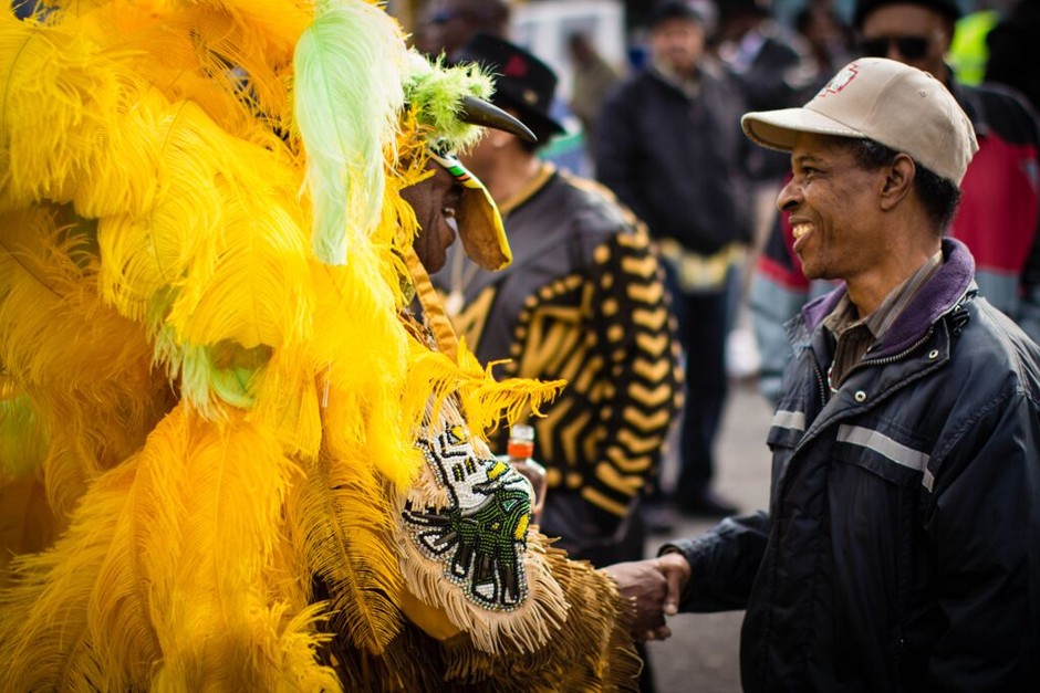 A Mardi Gras Indian shakes hands with a resident during the &quot;homegoing&quot; celebration for the late Wild Magnolias Chief Bo Dollis.