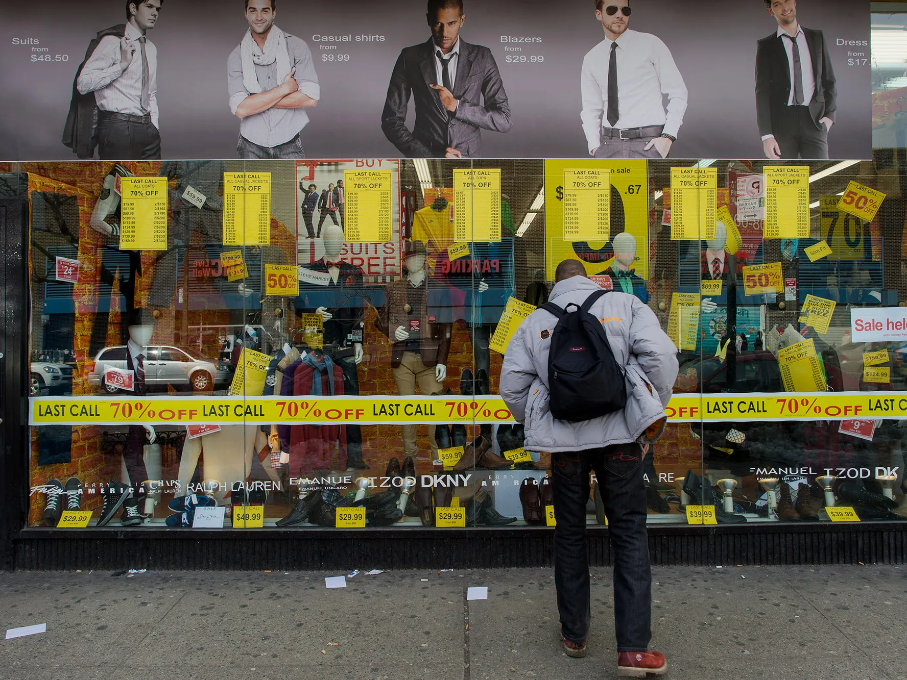 A pedestrian views a display window of a store in the Harlem neighborhood of New York.