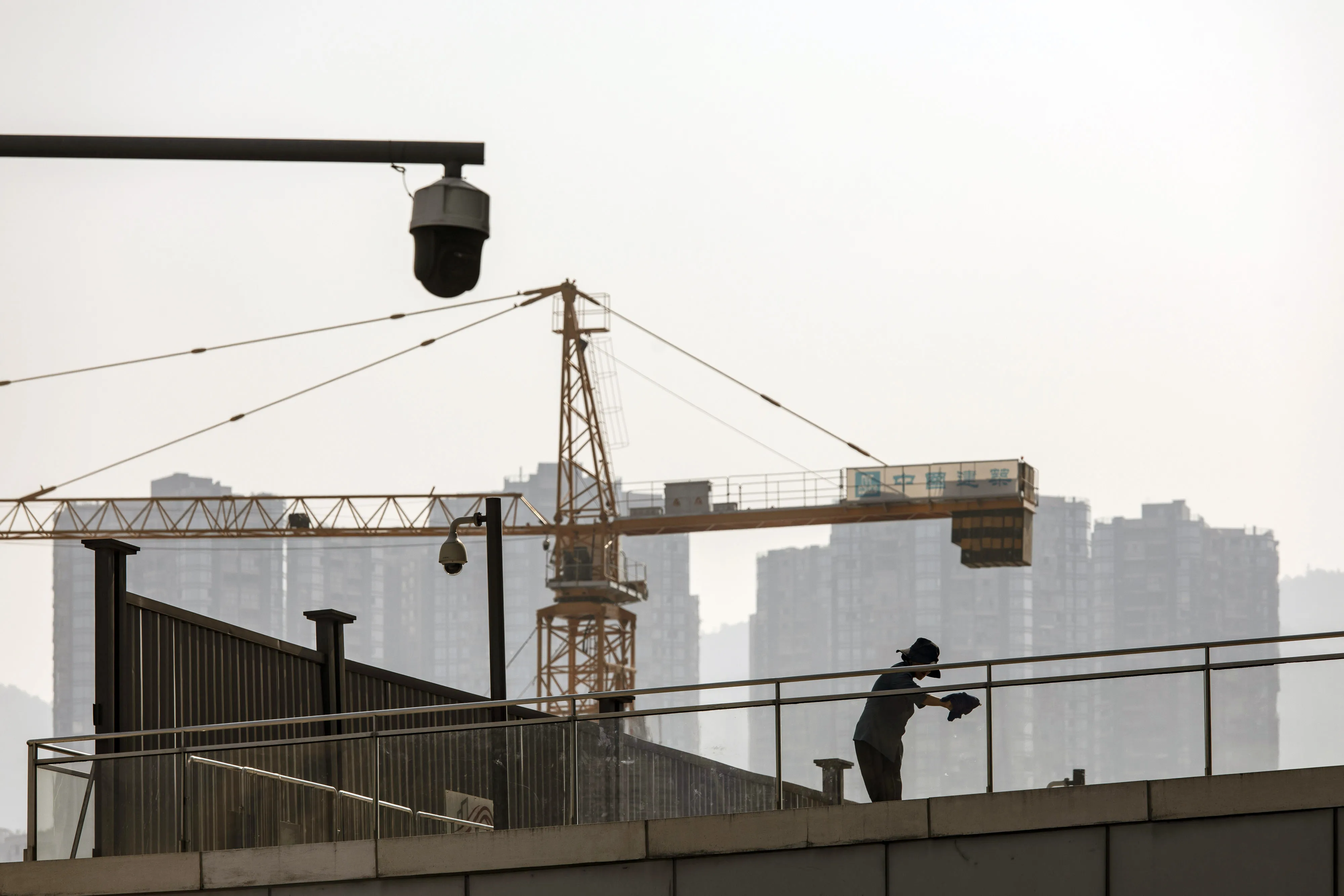 A worker cleans glass near a shopping center in Chongqing, China.