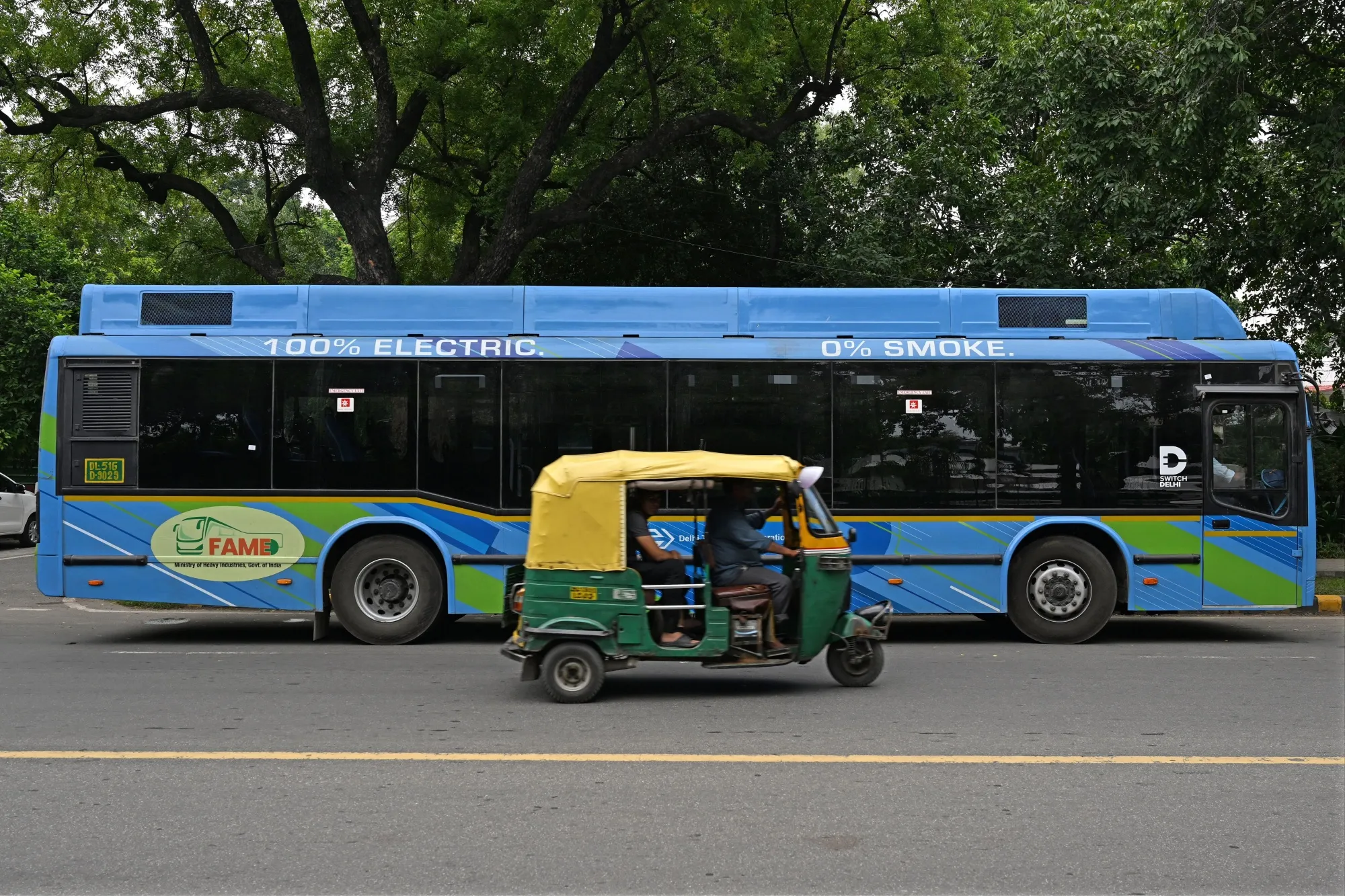An auto rickshaw rides past an electric bus&nbsp;in New Delhi.&nbsp;