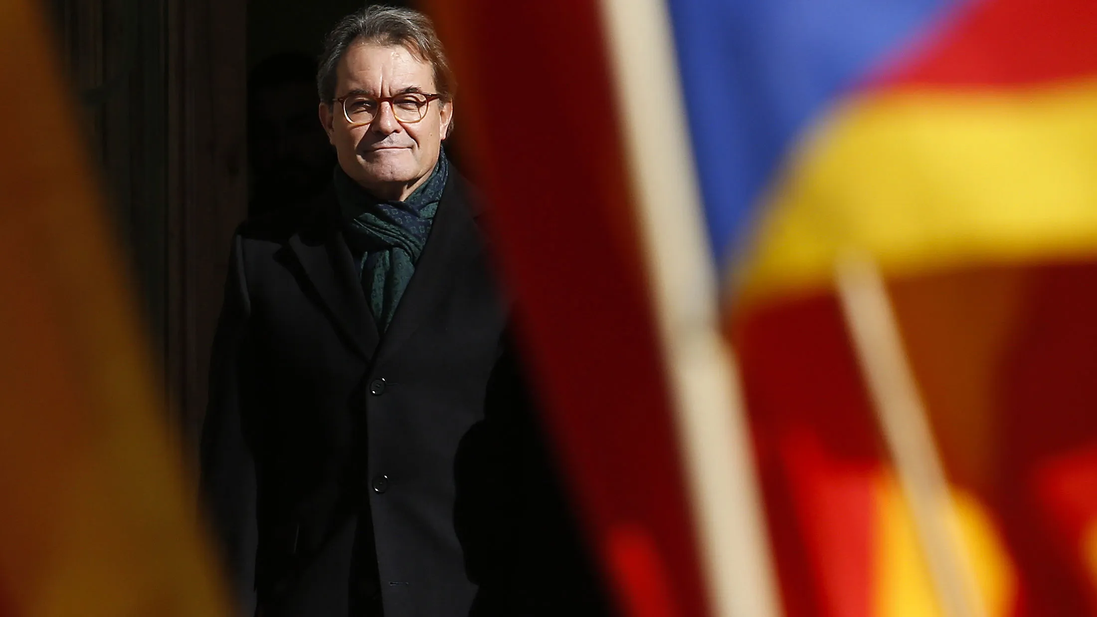 Artur Mas, former Catalan president, stands in front of Catalan independence flags waved by his supporters after visiting the Catalan high court in Barcelona on Feb. 6, 2017.
