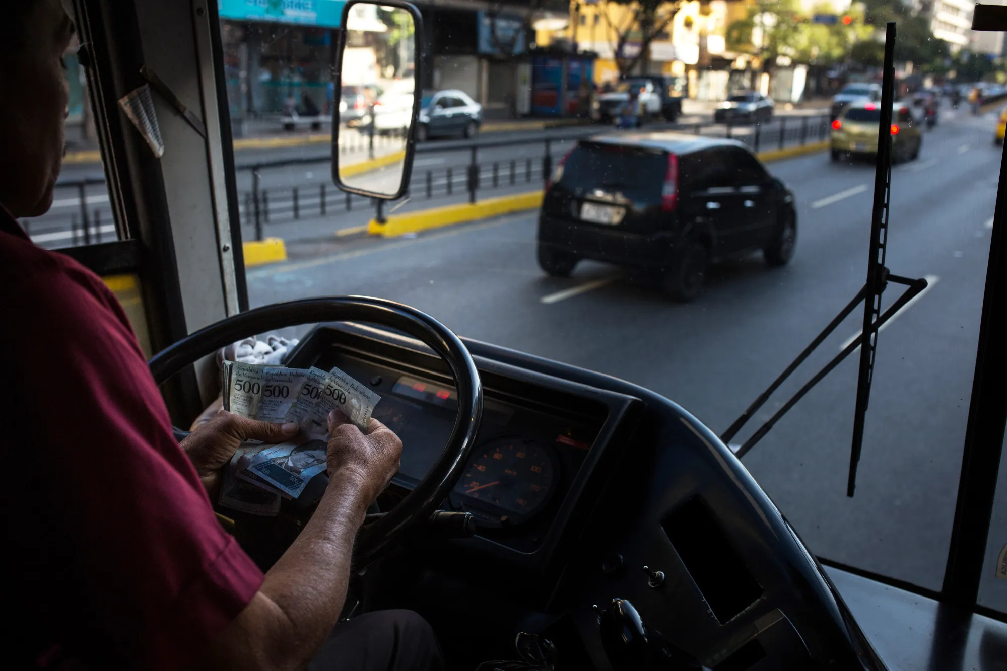 A bus driver counts bolivar banknotes in Caracas.