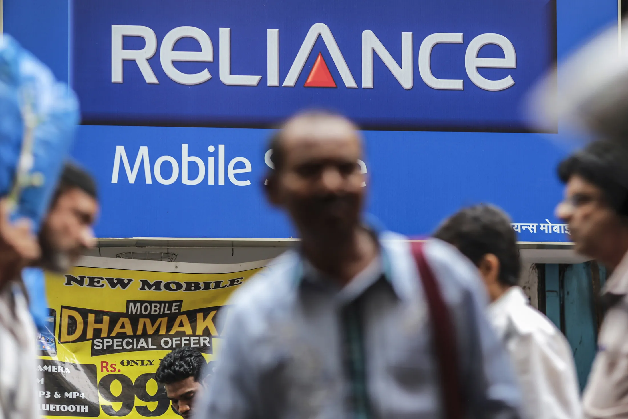 Pedestrians walk past a Reliance Communications Ltd. Mobile Store in Mumbai on Feb. 28.
