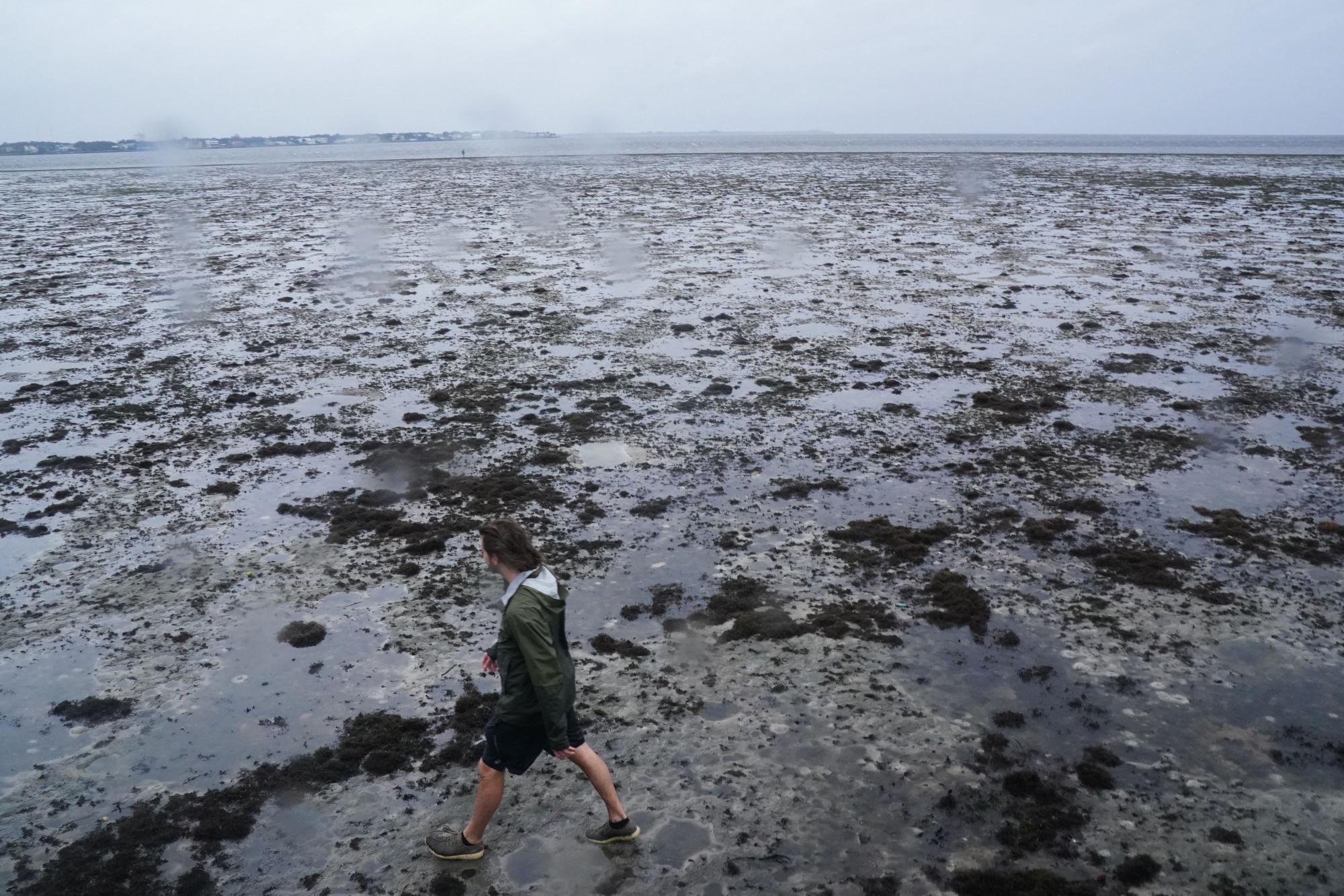 A man walks through the mudflats as the tide recedes as Hurricane Ian approaches on September 28&nbsp;in Tampa, Florida.&nbsp;