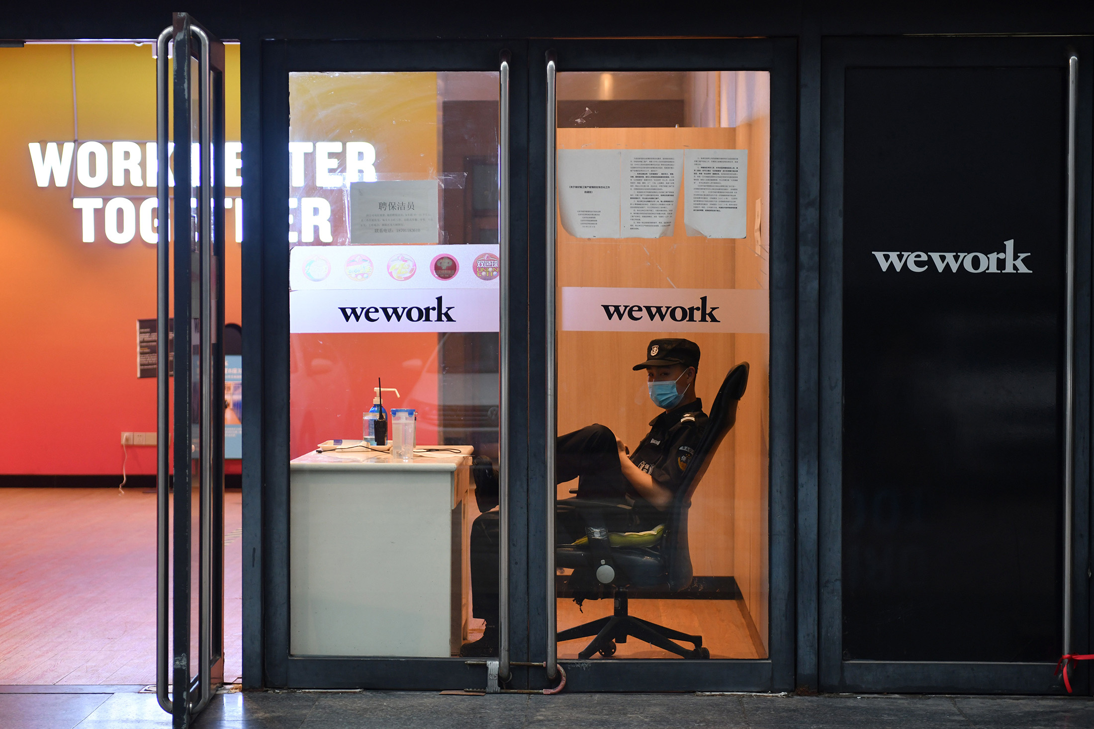 A security guard sits in the entrance to a WeWork office in Beijing on Aug. 12.
