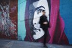 A man walks by a mural of activist Malala Yousafzai in Bushwick, a neighborhood in Brooklyn, New York.