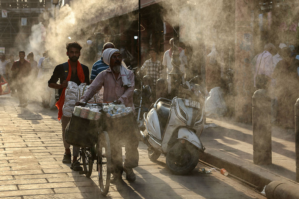 Water sprinklers cool people on a hot day in Varanasi in April.