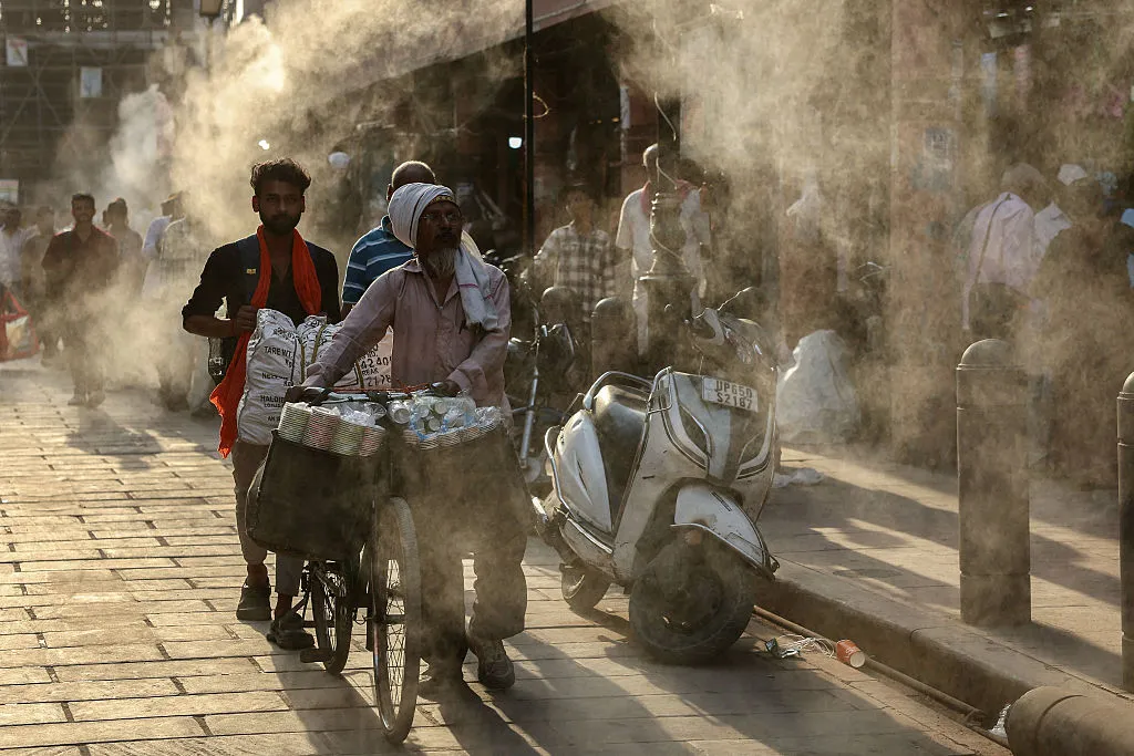 Water sprinklers cool people on a hot day in Varanasi in April.
