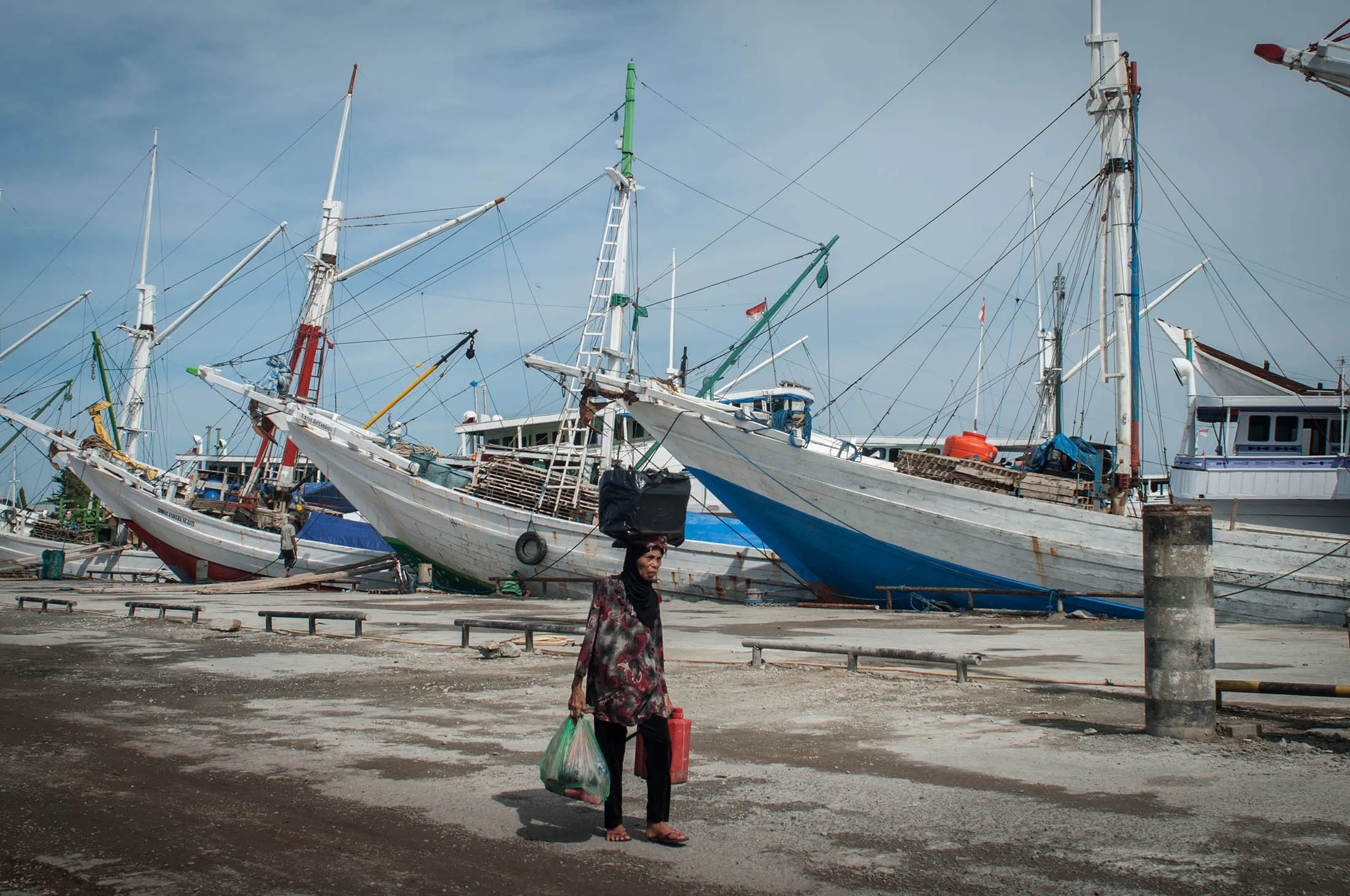 MAKASSAR, INDONESIA - 2016/03/19: A woman walks at Paotere Port. The Paotere Port well known as an old port and become one of tourism location in Makassar. Most of boats anchored at the port are traditional wooden boats known as pinisi.
