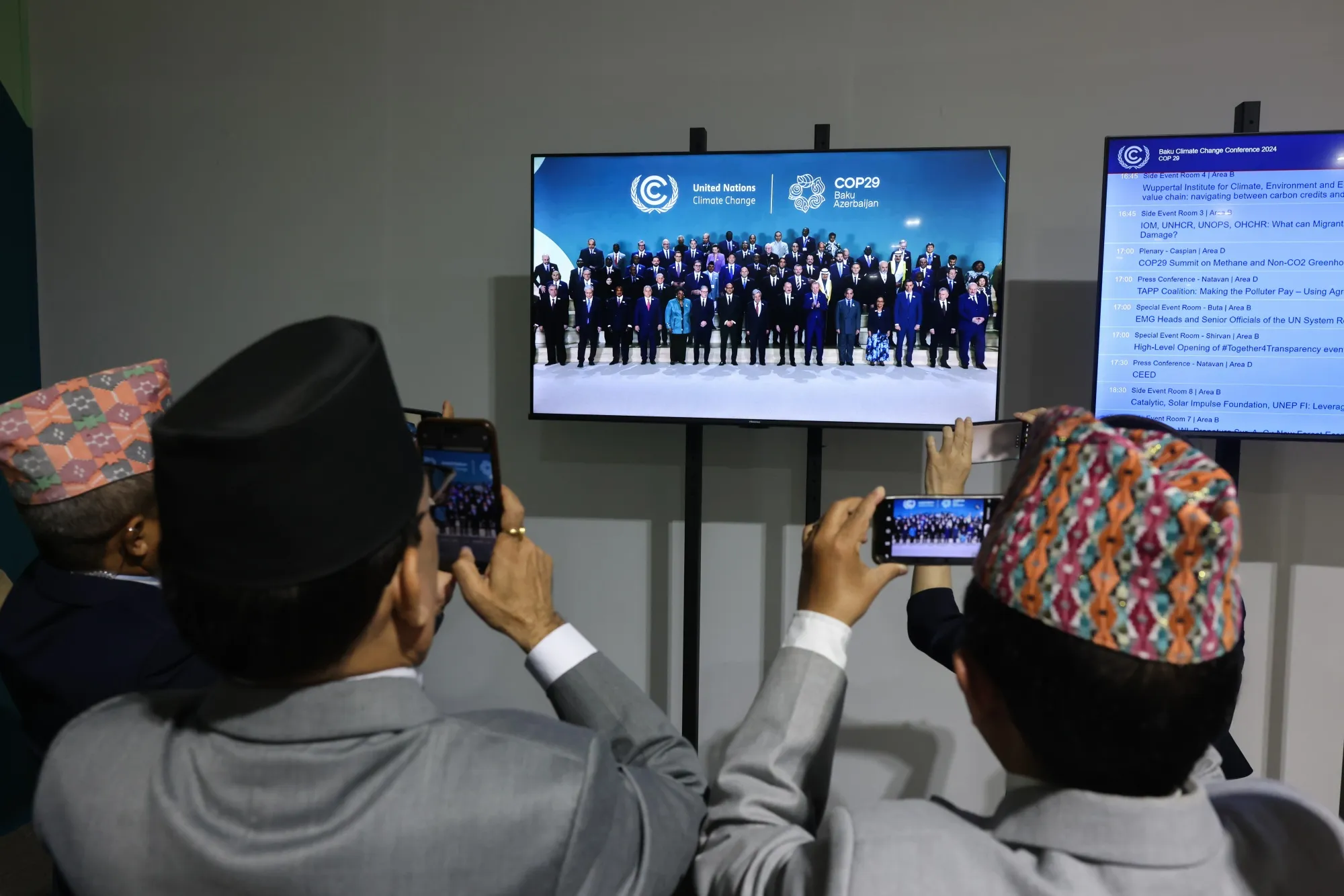 Attendees take photographs of a broadcast showing world leaders at the COP29 climate conference in Baku, Azerbaijan, on Tuesday.