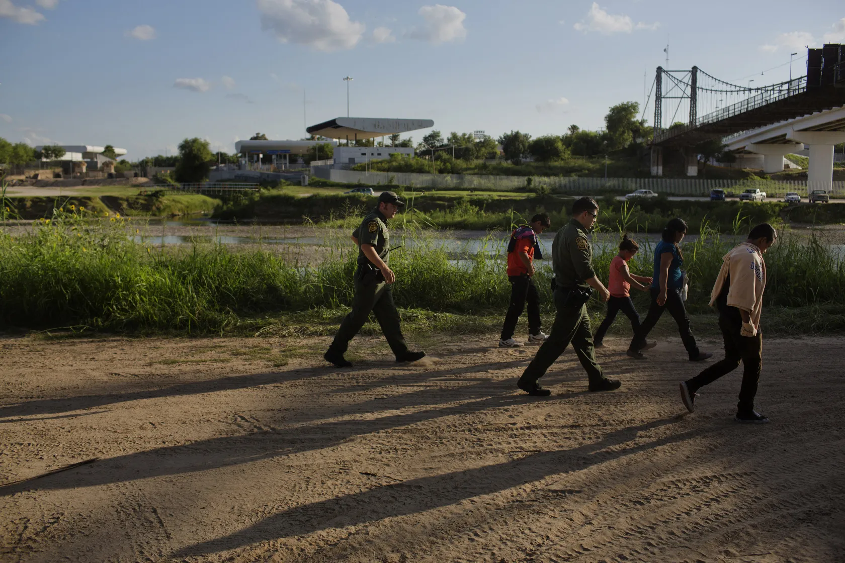U.S. Border Patrol agents escort a family of migrants that turned themselves in along the Rio Grande River in Roma, Texas.