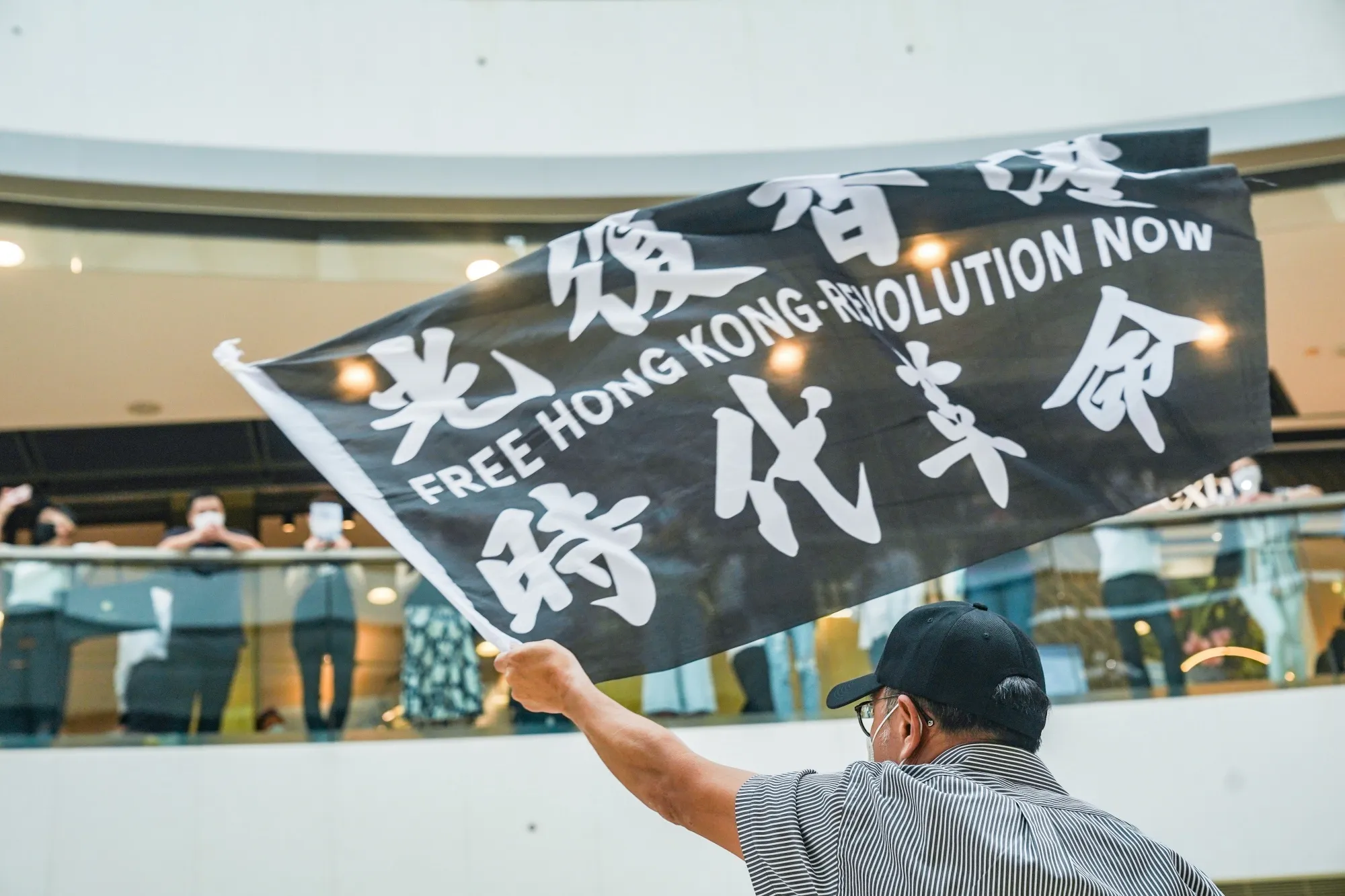 A demonstrator waves a flag reading "Free Hong Kong, Revolution Now" during a lunchtime protest at the International Finance Center (IFC) shopping mall in Hong Kong&nbsp;on May 29.