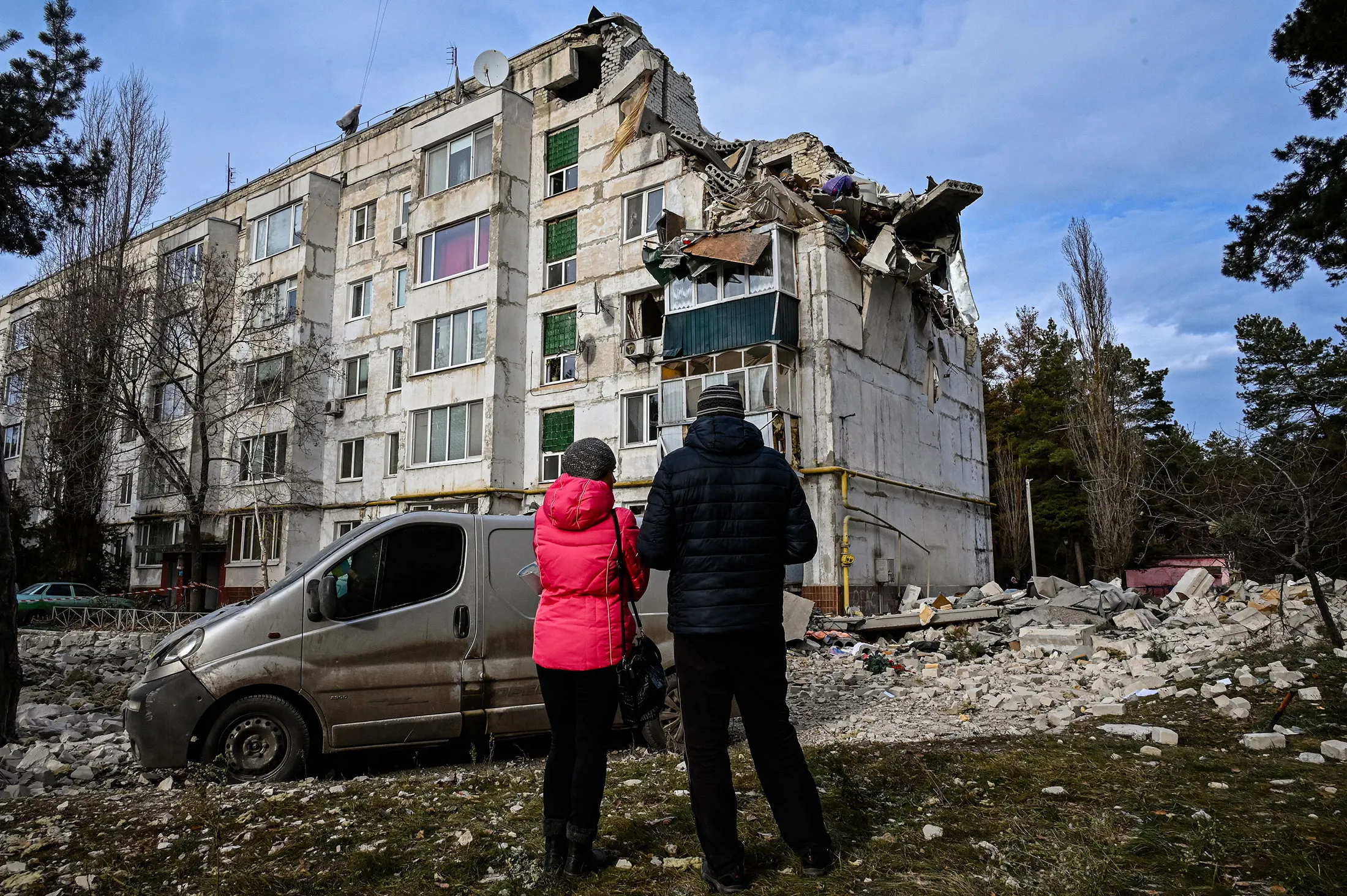 Local residents look at a residential building damaged by a missile attack in the village of Kluhyno-Bashkyrivka, Kharkiv region, on Dec. 2.
