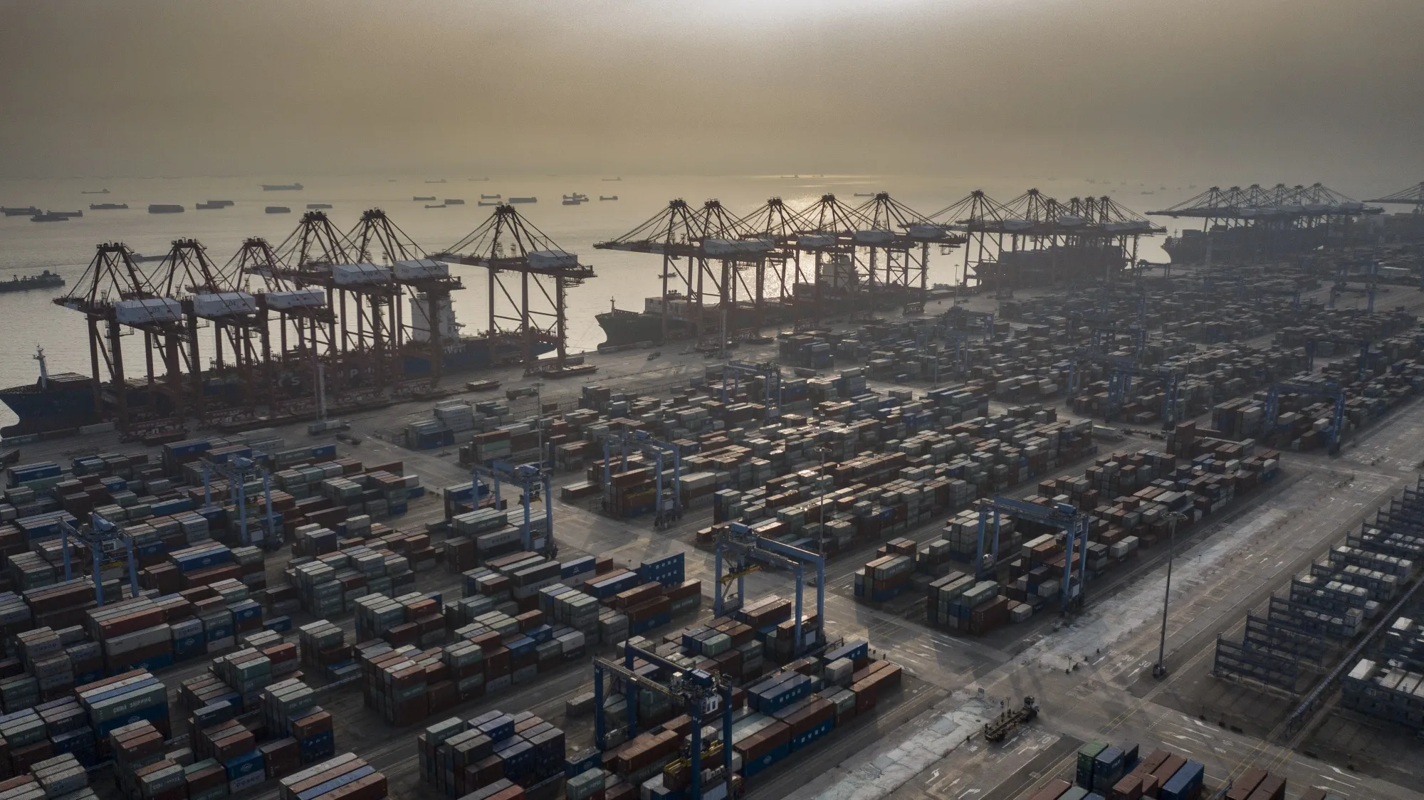 Shipping containers are stacked near gantry cranes at the Port of Nansha, in the Nansha district of Guangzhou, China.