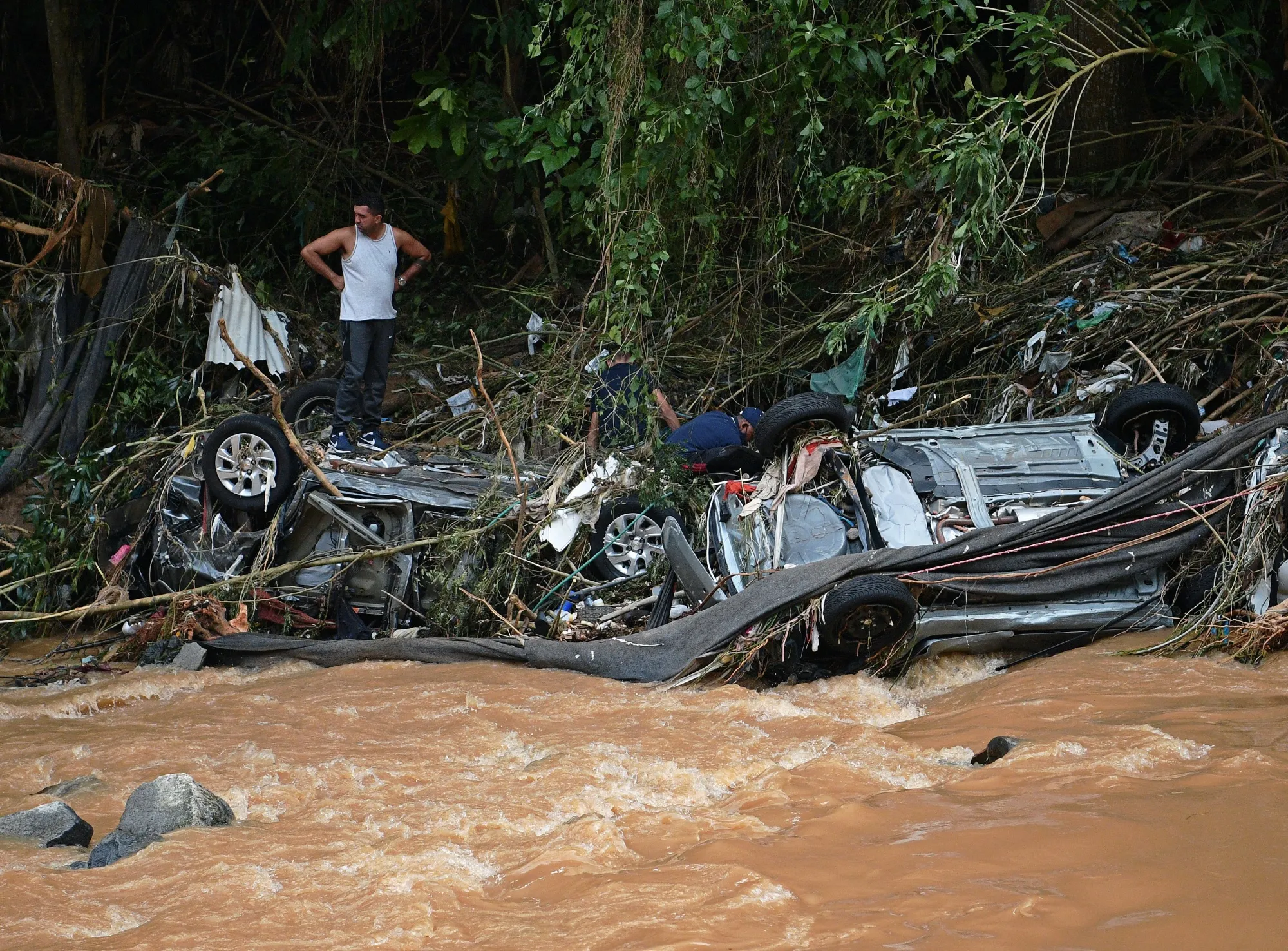 People try to rescue items from cars destroyed by a flash flood in Petrópolis, Brazil, in early&nbsp;2022.