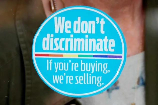 A hair salon displays a window sticker declaring “We don’t discriminate. If you’re buying, we’re selling” on April 22 in Jackson, Miss.