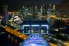 The Singapore Flyer operates at night as the Marina Bay Sands hotel and casino, left, and commercial buildings in the the central business district are illuminated in the background at night in Singapore, on Thursday, Feb. 18, 2016. Singapore's Infocomm Development Authority plans to auction additional mobile spectrum this year as it seeks to lure a new entrant to compete with the city's three existing providers.