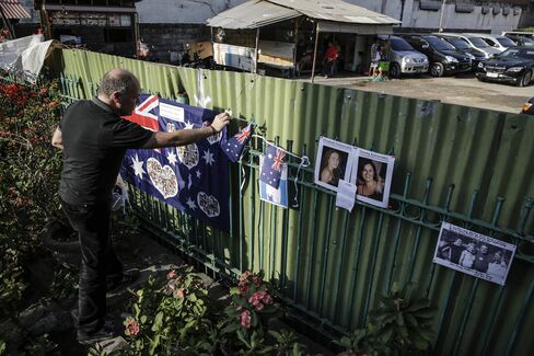 A man puts an Australian flag across the street from the Bali Bombing Memorial Monument in Kuta.