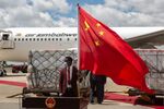 A man holds a Chinese flag in front of the shipment of Sinovac and Sinopharm vaccines at Harare International Airport in&nbsp;Zimbabwe, in 2021.&nbsp;