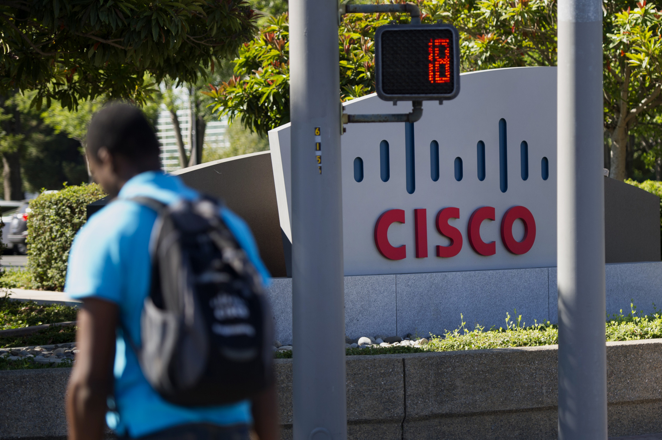 A pedestrian walks past Cisco Systems headquarters in San Jose, California.