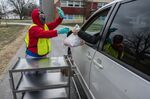 A Jefferson County Public Schools nutritional assistant hands out student meals to-go at of Crums Lane Elementary School in Louisville, Kentucky.