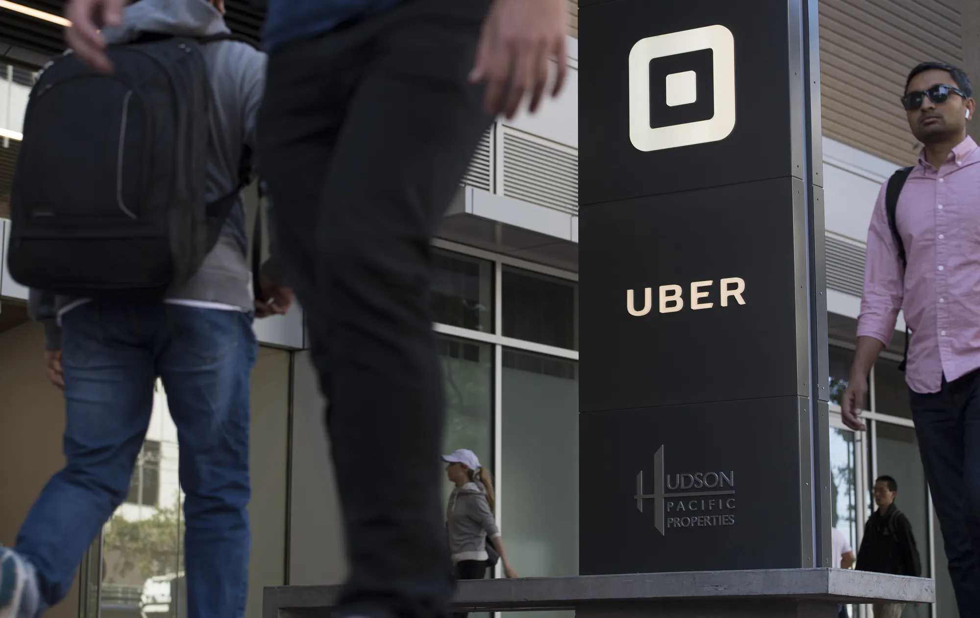 Pedestrians walk past the Uber Technologies Inc. headquarters building in San Francisco, California.