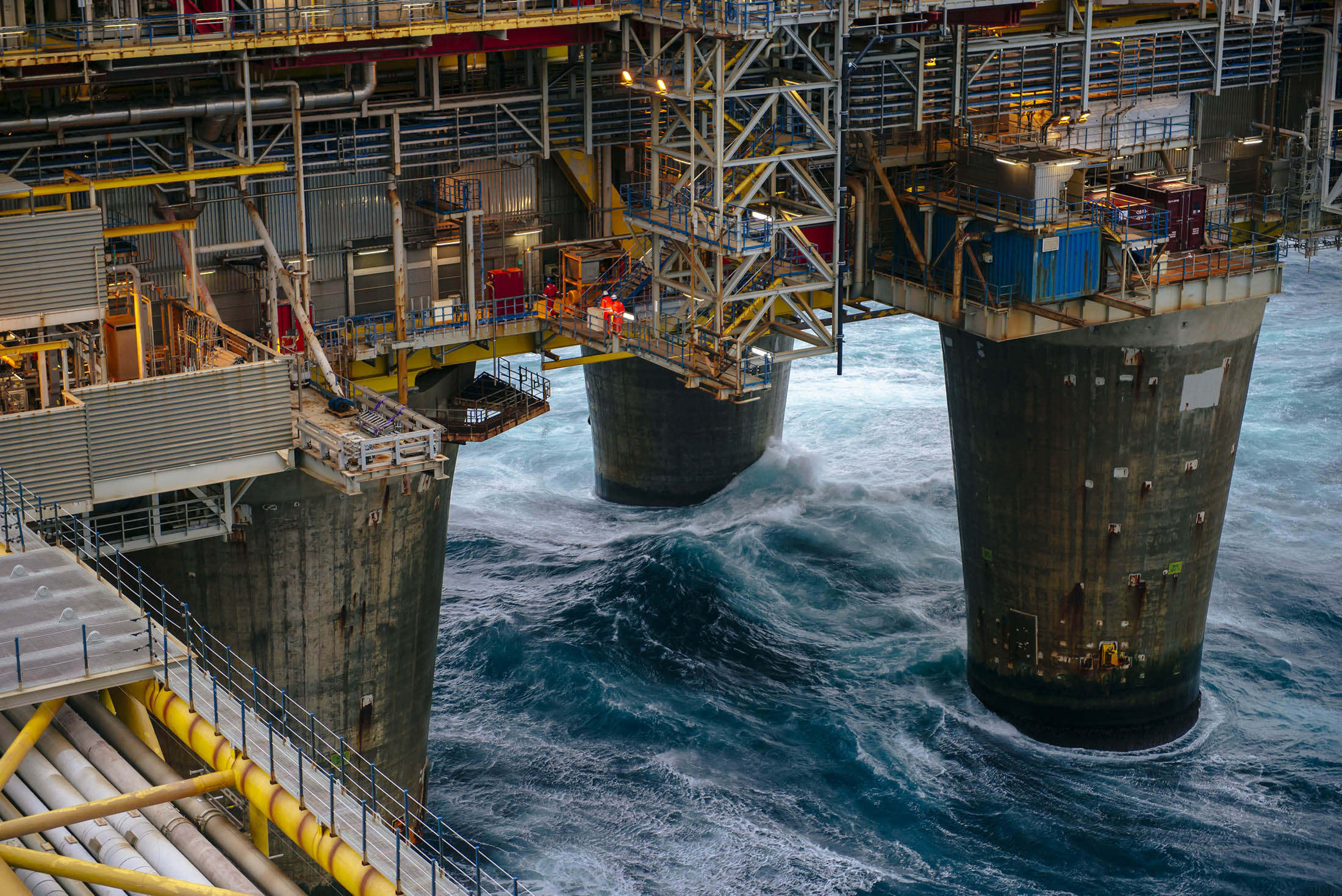Workers move along an access way above the giant supporting legs of the Oseberg A offshore gas platform in the Oseberg North Sea oil field 140kms from Bergen, Norway.
