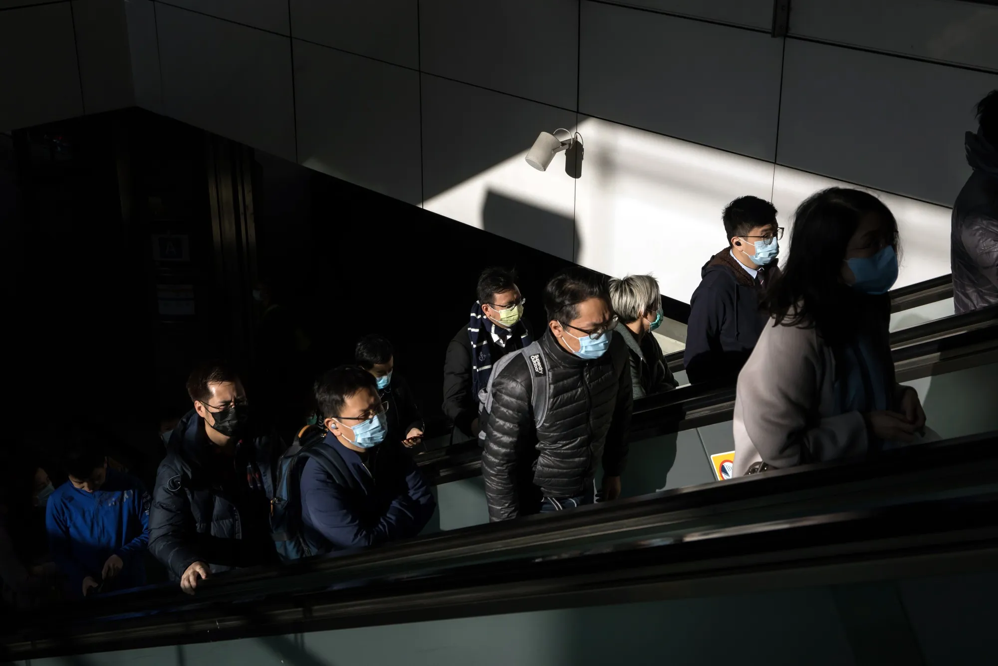 People wearing protective masks ride on escalators in Hong Kong.