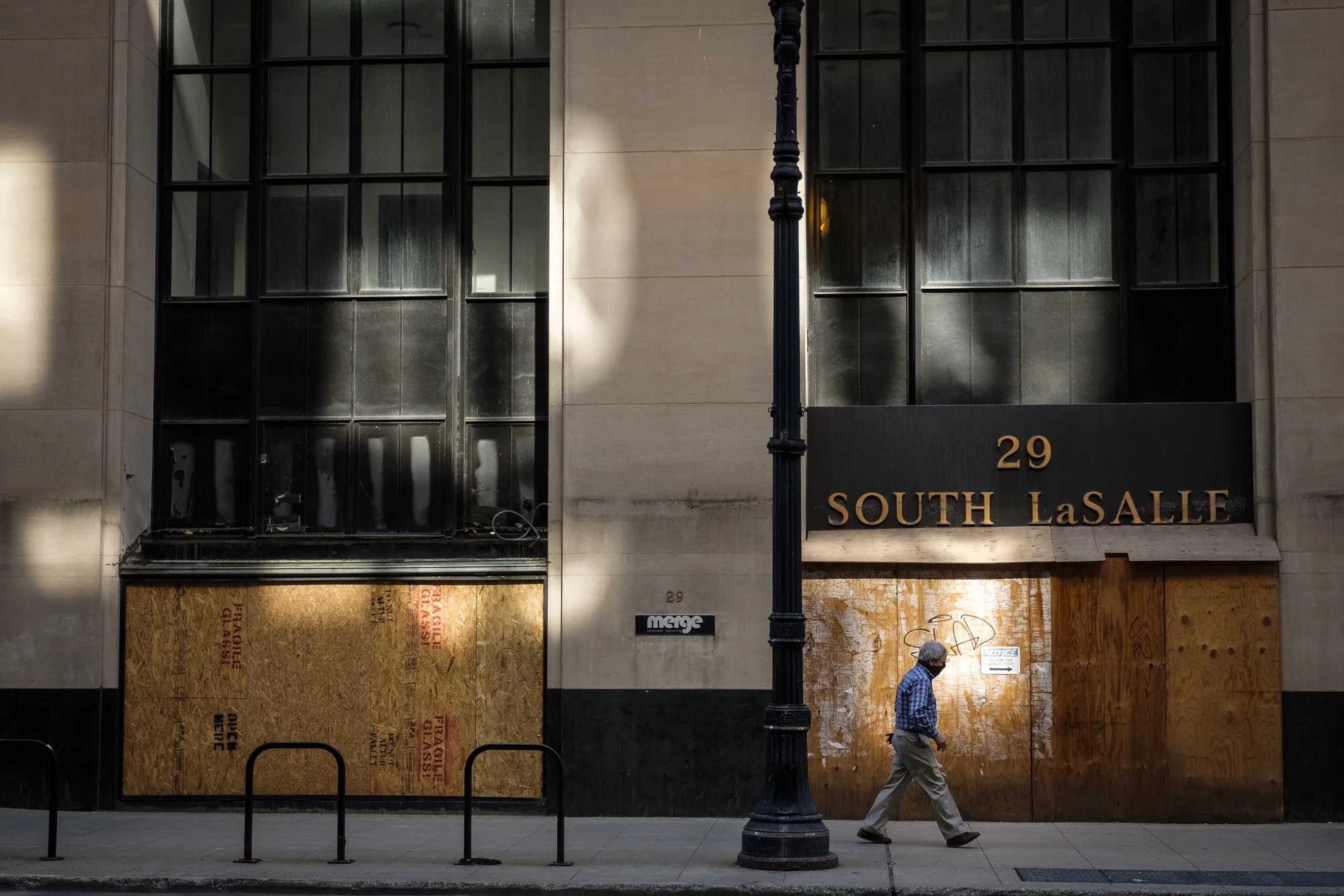 A pedestrian wearing a protective mask passes up a boarded-up store in Chicago, Illinois on&nbsp;May 7.&nbsp;