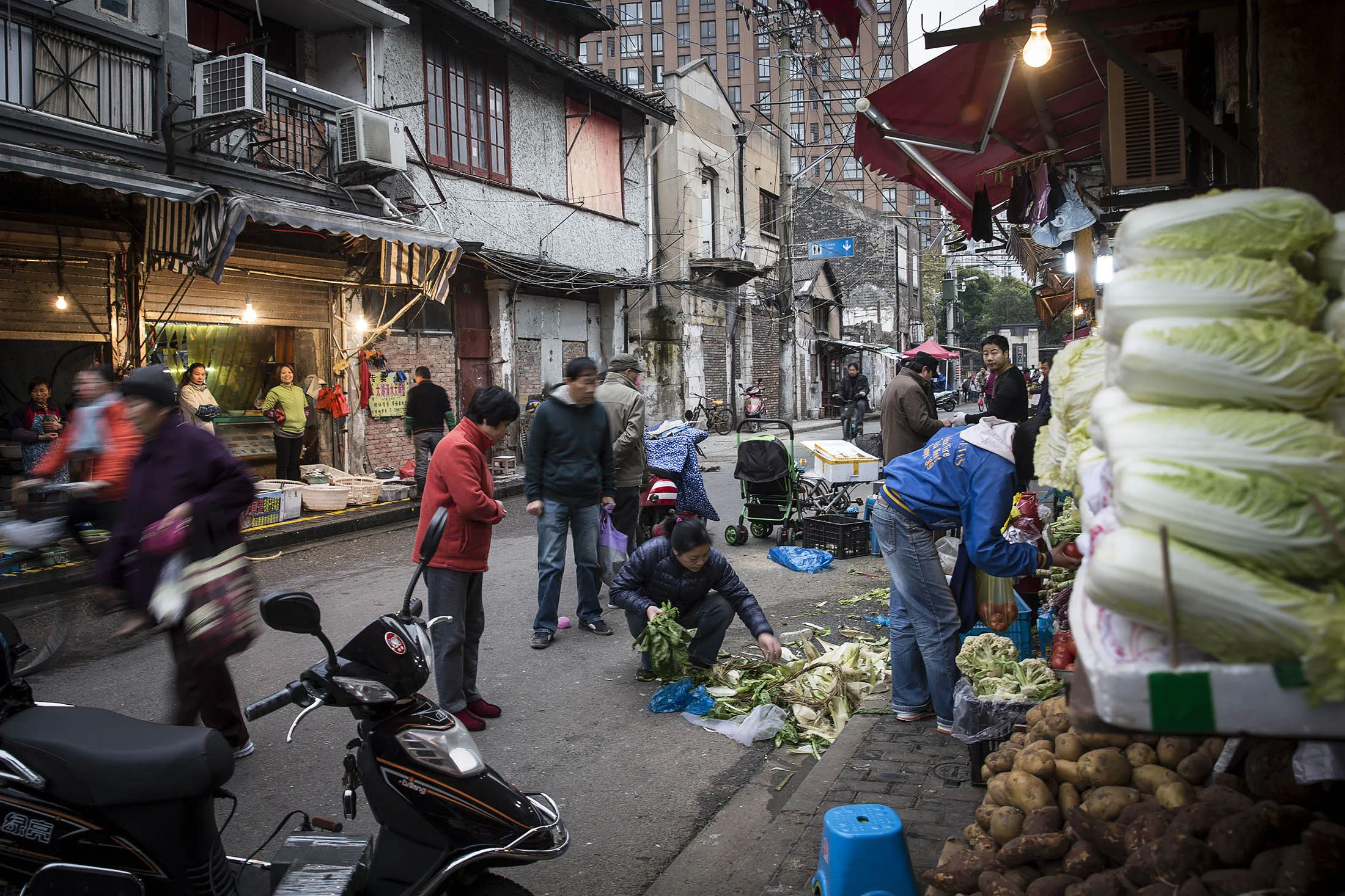 A woman sorts through vegetables at a fresh food market in Shanghai, China, on Saturday, Dec. 5, 2015. Premier Li Keqiang is facing a precarious balancing act as he eases fiscal policy to meet a target of 6.5 percent annual economic growth for the next five years, while reining in a debt pile that is estimated to be already more than twice the size of the world's second-largest economy.
