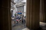 Pedestrians carry umbrellas while passing in front of the New York Stock Exchange (NYSE) in New York, U.S., on Friday, May 5, 2017. U.S. stocks fluctuated with the dollar and Treasuries as a rebound in hiring added to optimism that the economy is on firm footing, boosting speculation the Federal Reserve will raise interest rates.