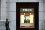 A pedestrian walks past the headquarters of Nomura Securities Co., a unit of Nomura Holdings Inc., in Tokyo, Japan.