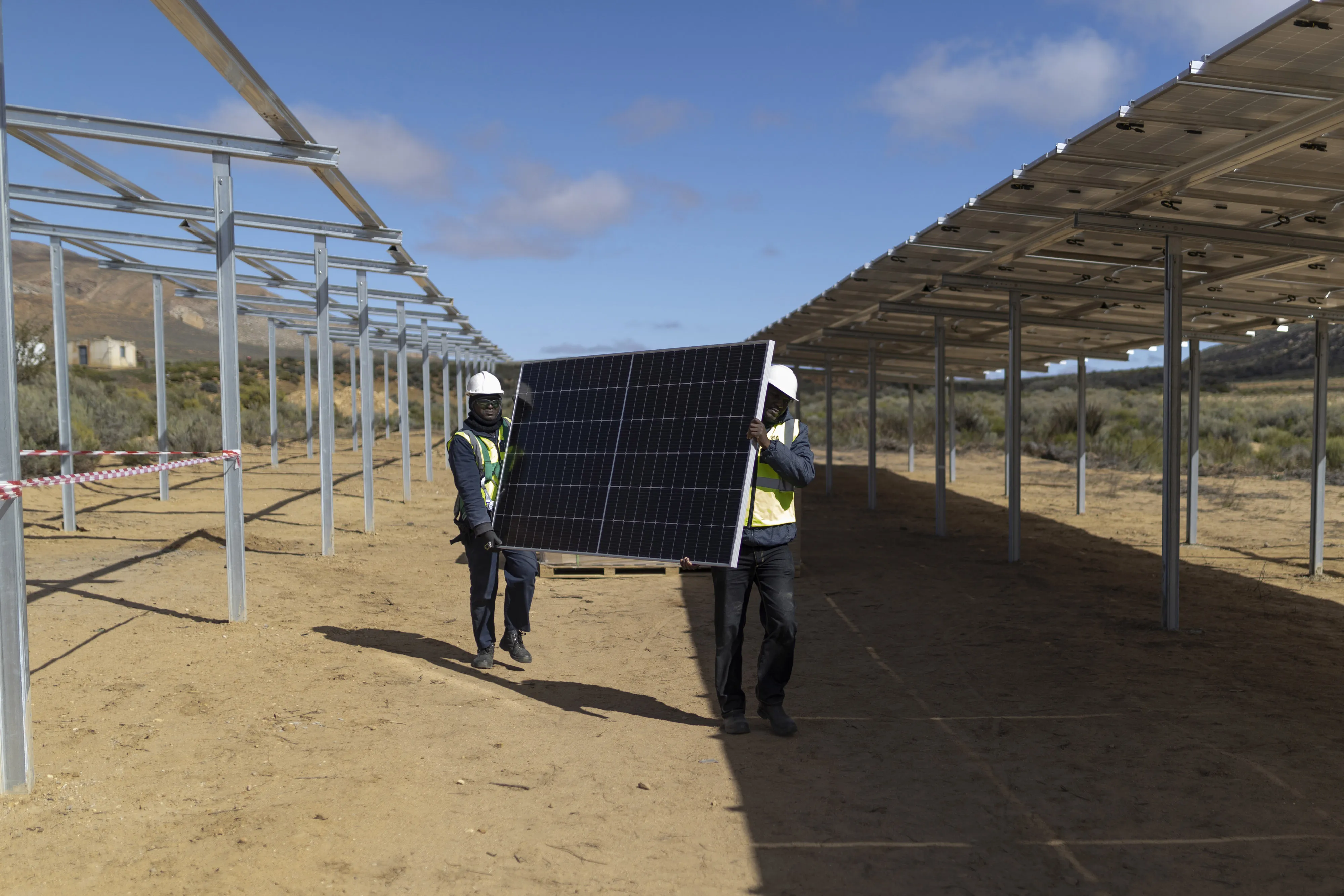 Workers carry a solar panel for installation at a farm in Groenfontein, South Africa.