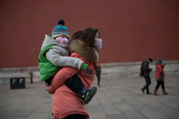 A woman and child walk in the Forbidden City during heavy pollution in Beijing