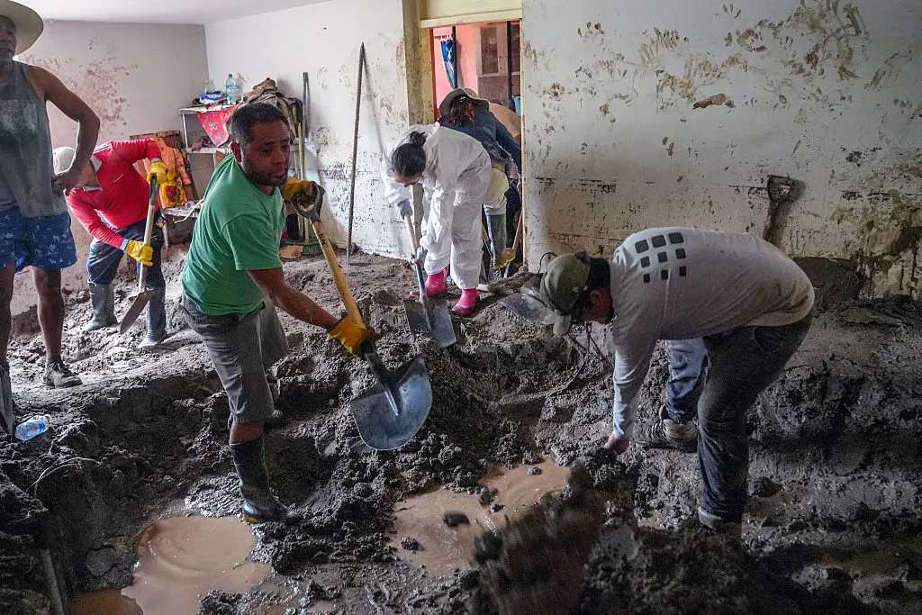 Locals remove mud from inside a house following heavy rains in Arequipa, Peru.