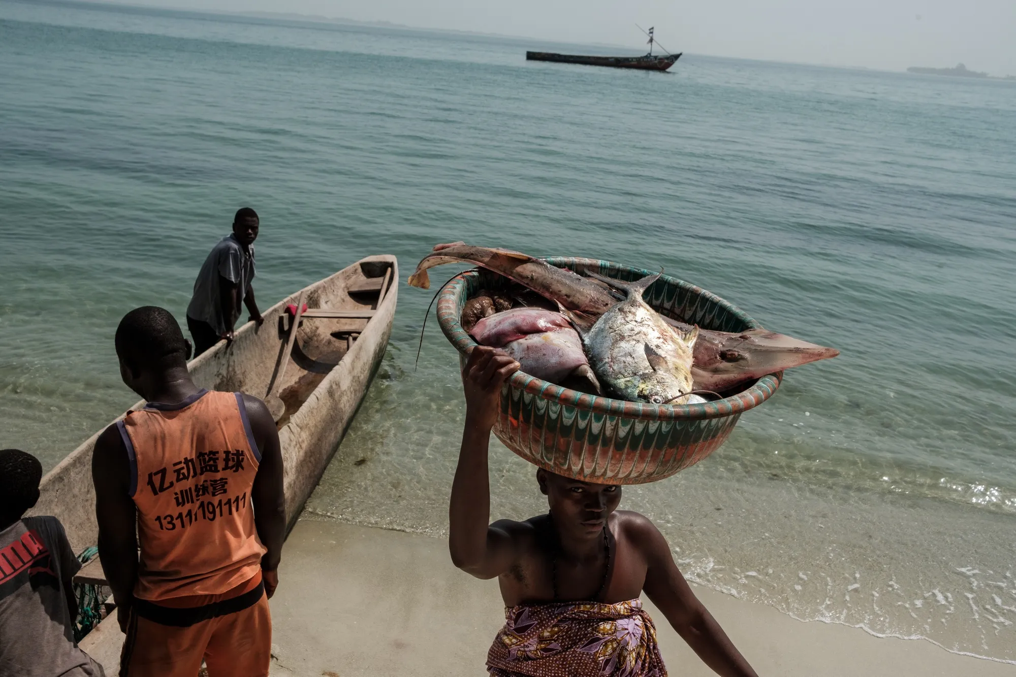 SEI ISLAND, SIERRA LEONE - FEBRUARY 16: A women carries a basket of freshly caught fish from a boat on Sei island where the local community has been actively protecting its seagrass as it directly effects their fish stocks and the health of the fish they rely on on Sei, Sierra Leone on February 16, 2023 Photographer: The Washington Post/The Washington Post