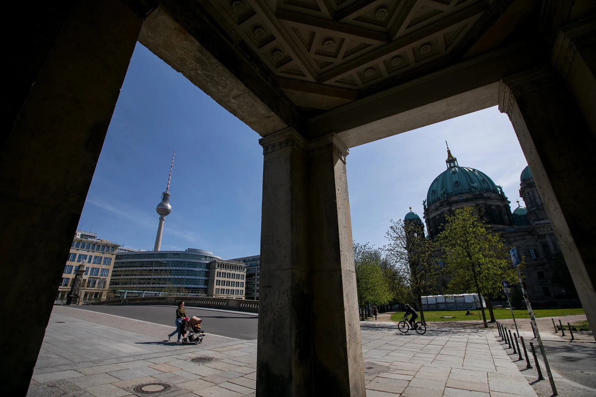 A pedestrian pushes a baby stroller near the Fernsehturm Tower, left, and Berlin Cathedral in Berlin.